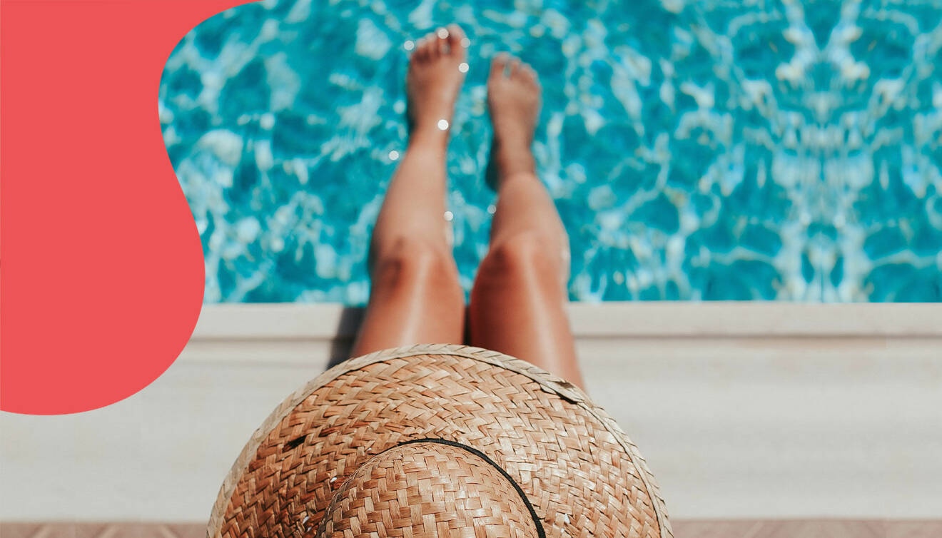 En kvinna i solhatt doppar fötterna i poolen.