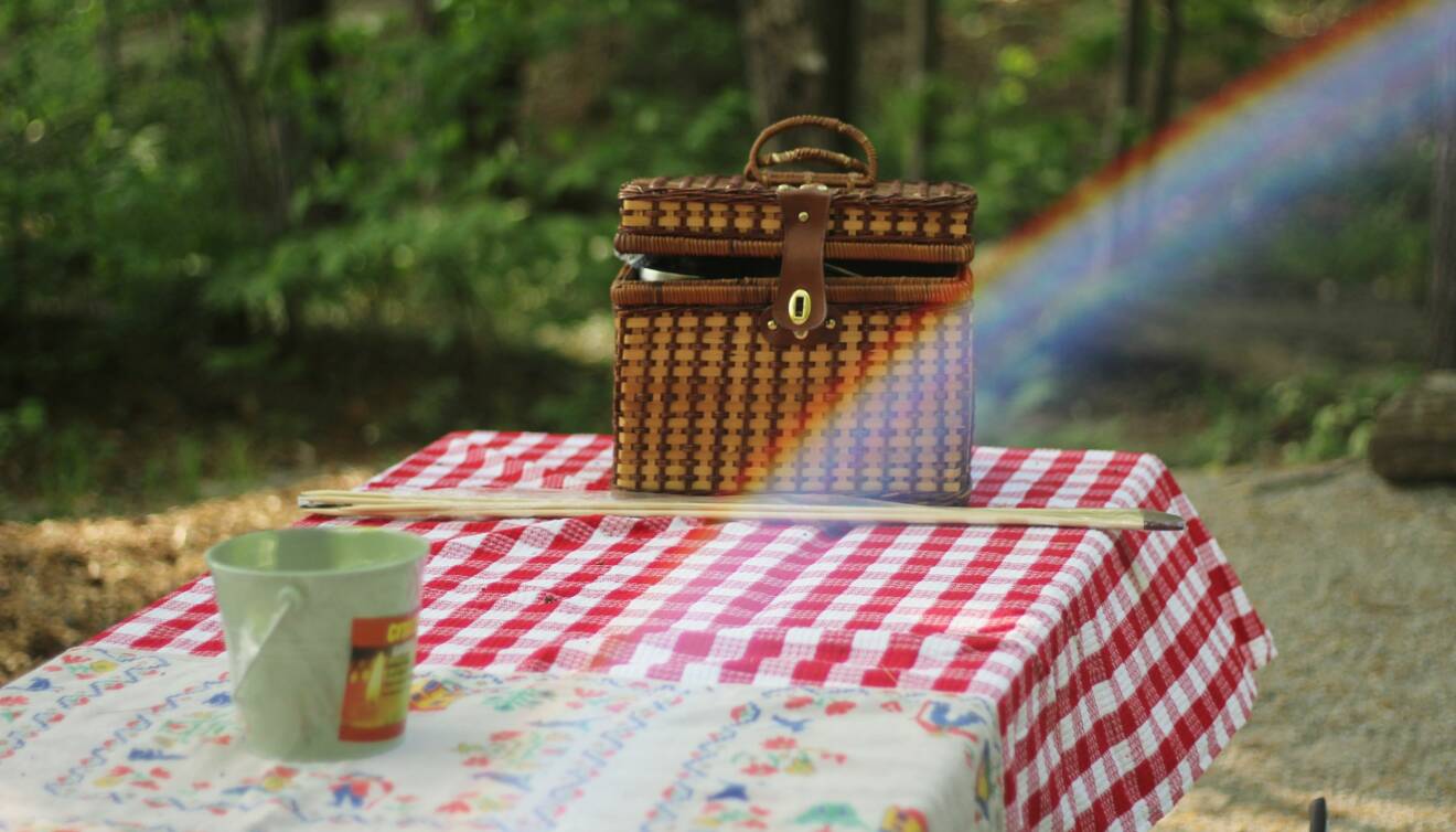 En korg och en kaffekopp på picnicbordet.