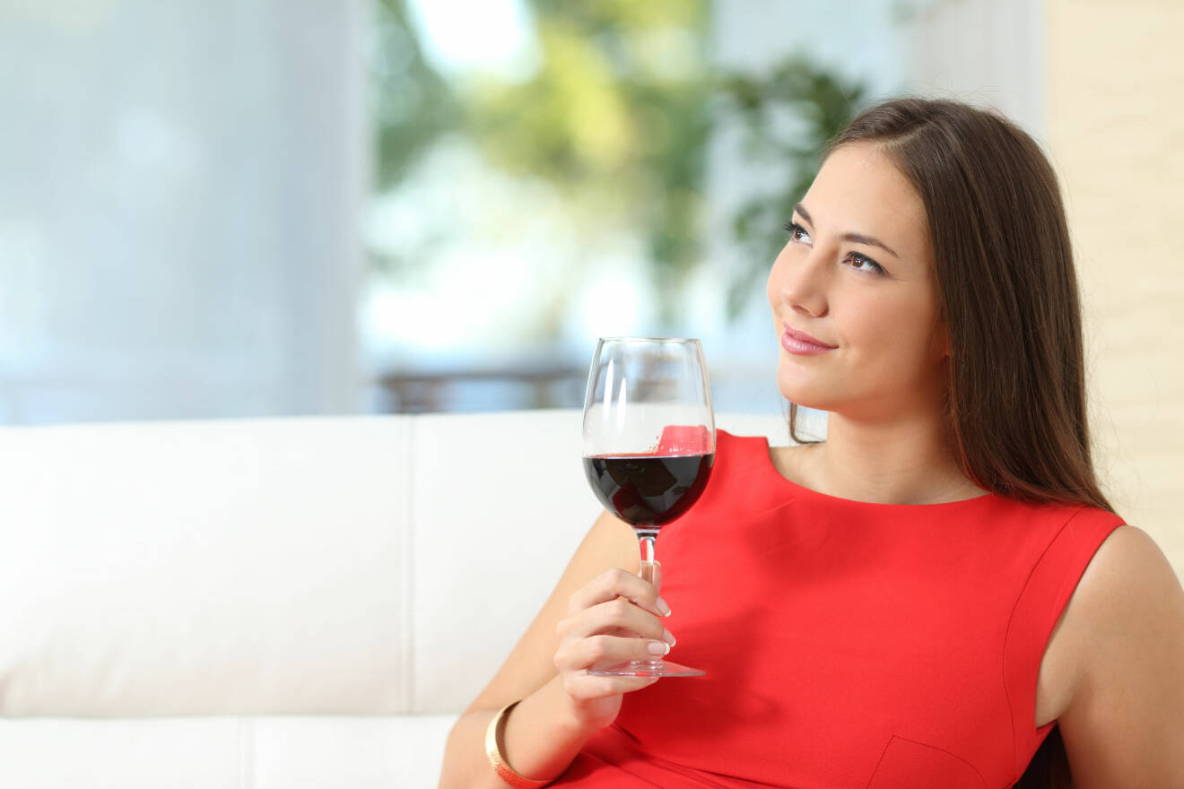 Kvinna dricker vin i soffa.