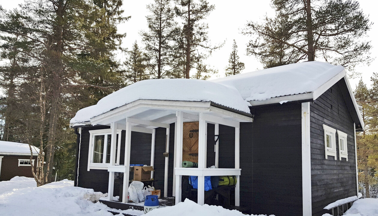 Bild på blå fjällstuga med snö på taket.