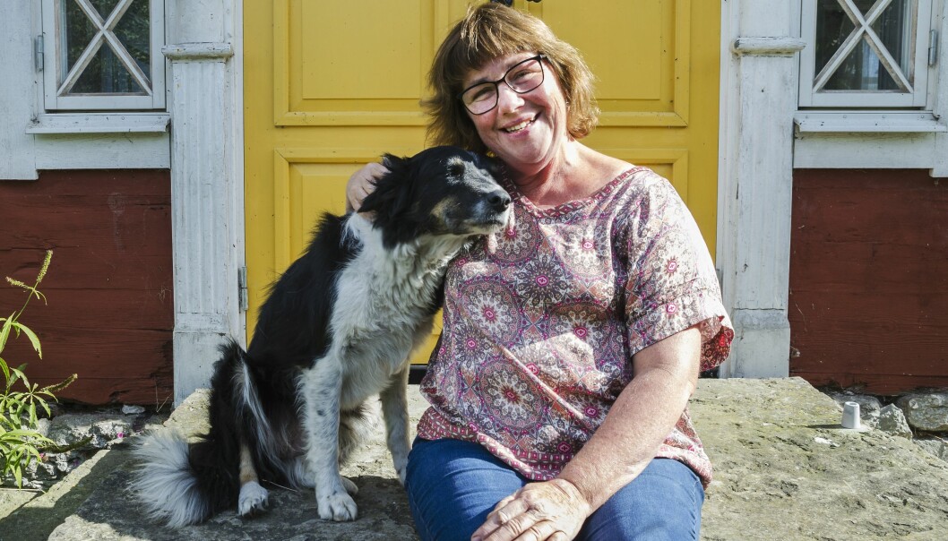 Kerstin med vallhunden Zoe på gården. Foto:Kristina Wirénm Kerstin på trappan bakom gul dörr, kelar med sin hund.
