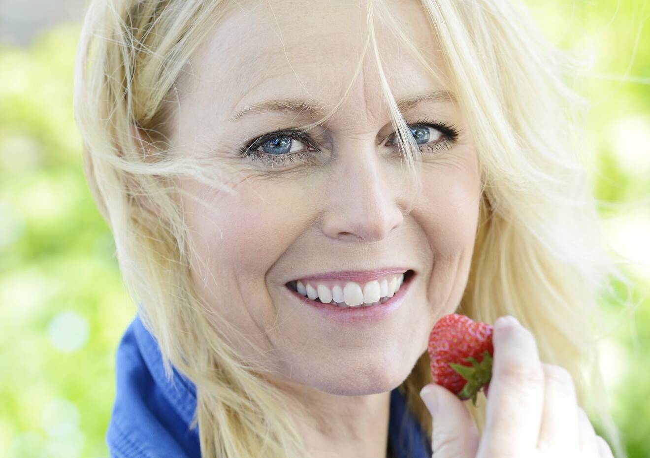 Porträtt på glad Annika med jordgubbe.