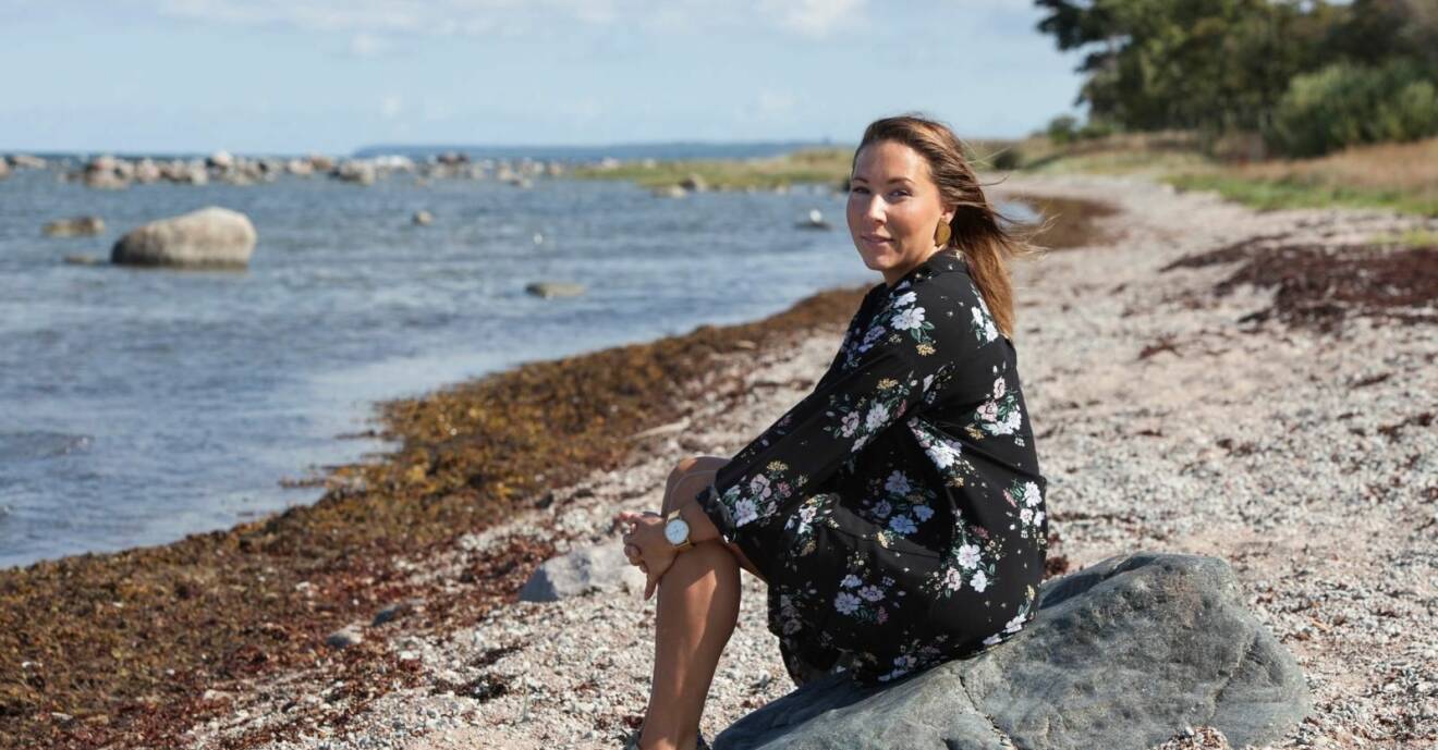 Sofie sitter på en sten på stranden.