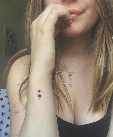 Amanda har valt att tatuera sig för att visa sitt stöt för Project Semicolon. Projektets syfte är att stödja människor som lidit eller lider av psykisk ohälsa. Semikolonet symboliserar en mening som författaren kunnat avsluta, men valt att fortsätta på.