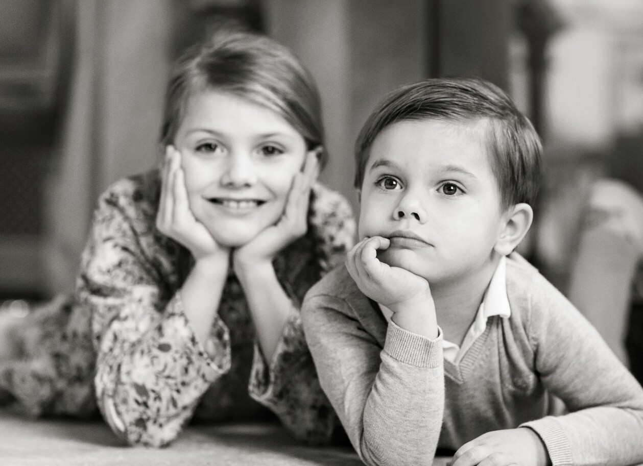 Det allra finaste de gjort tillsammans, barnen Estelle och Oscar. Foto: Linda Broström/Kungahuset Fundersam Prins Oscar och glad prinsessan Estelle ligger och stöttar sina huvud med händerna på svartvit bild.