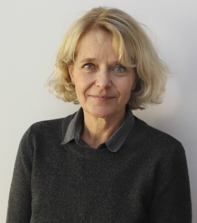 Clara Hellner, professor i barn- och ungdomspsykiatri vid Karolinska Institutet. Clara Hellner står framför en vit vägg och tittar in i kameran.