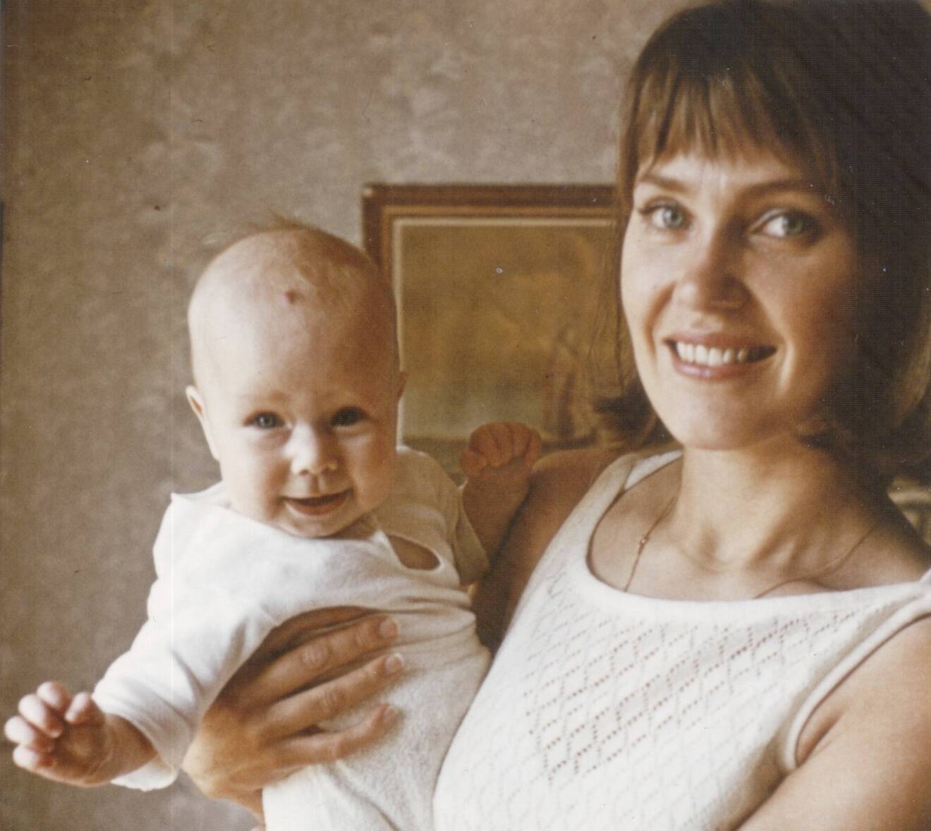 Mamma håller upp en glad Charlotte Sirc som liten bebis.