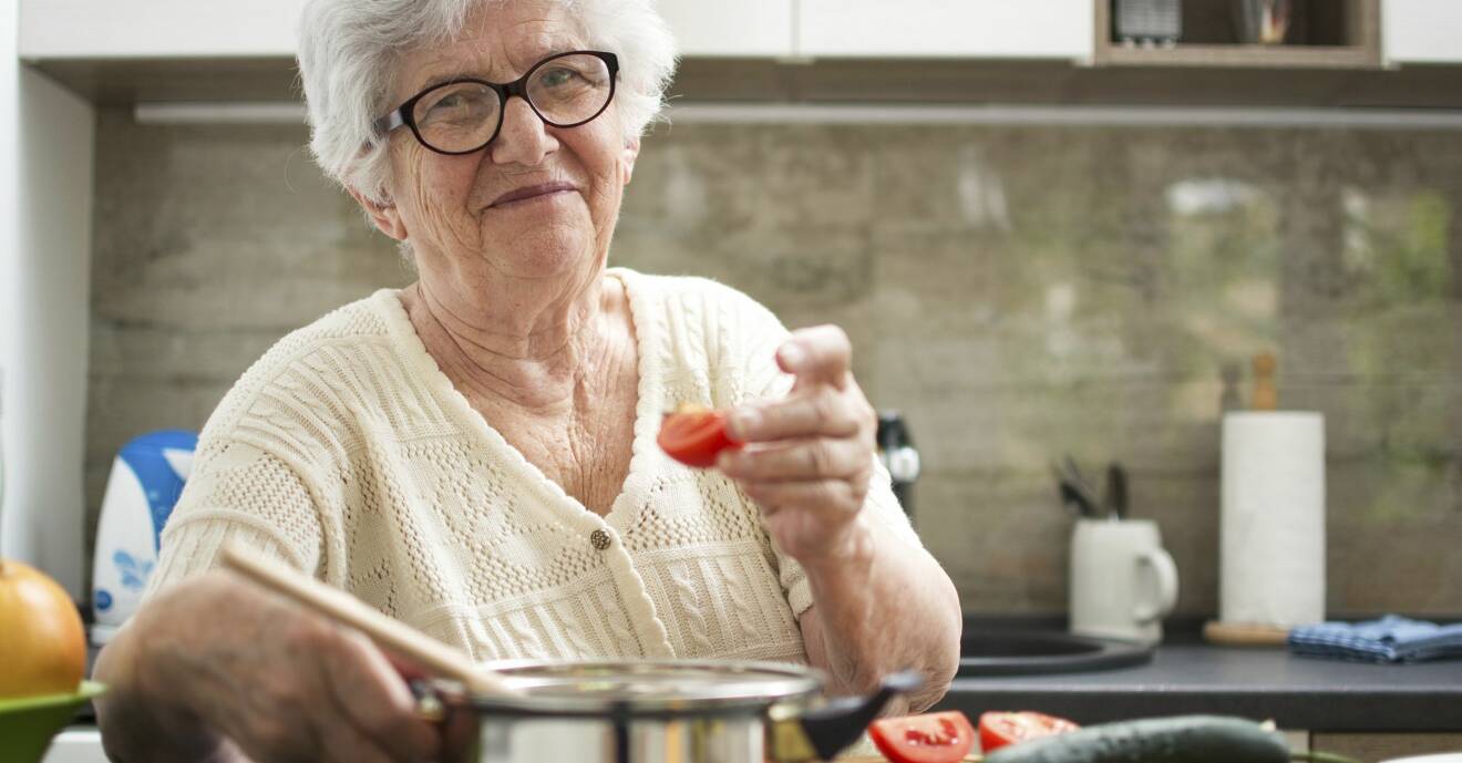 En äldre kvinna lagar mat i ett kök.