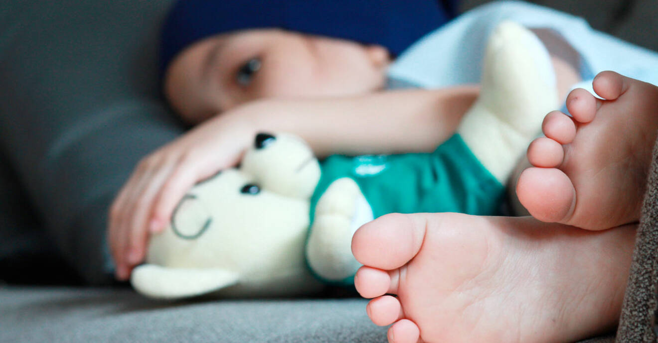 Ett barn med cancer som ligger uppkrupet i sängen.