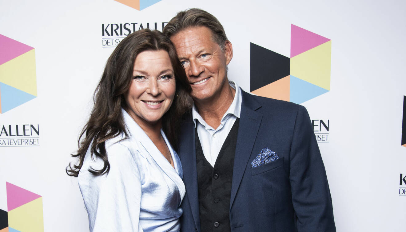 Lotta Engberg och Mikael Sandström står nära och kärleksfullt intill varandra på röda mattan.