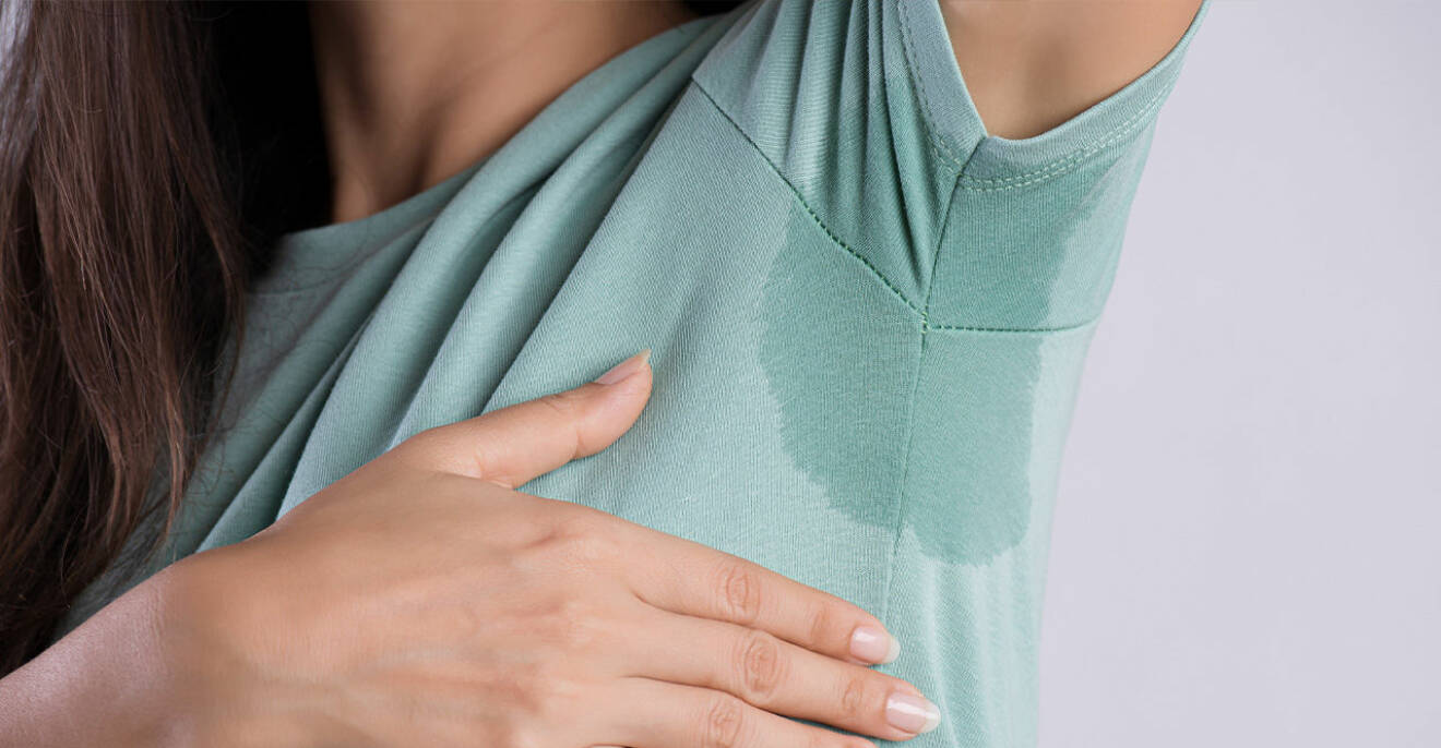 En kvinna med rejäla svettningar under armarna på grund av en deodorant som inte riktigt fungerar som den ska.
