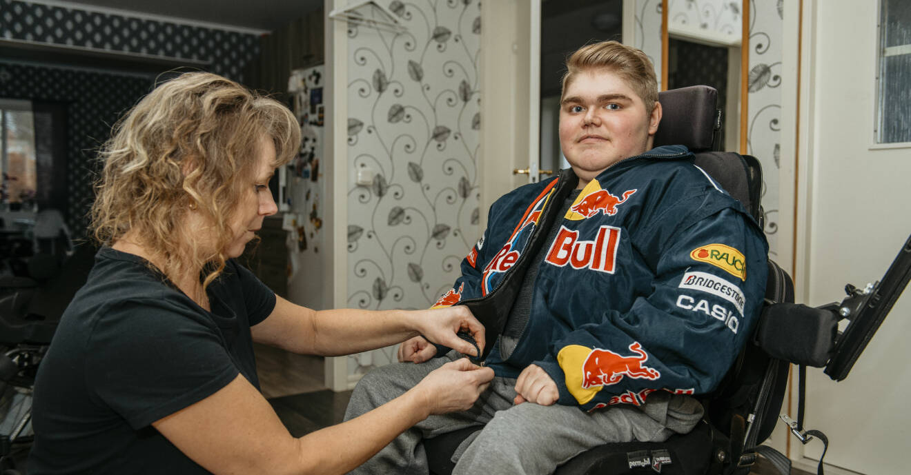 Lena Aftelöv hjälper sonen Marcus Aftelöv, som sitter i rullstol, att stänga jackan.