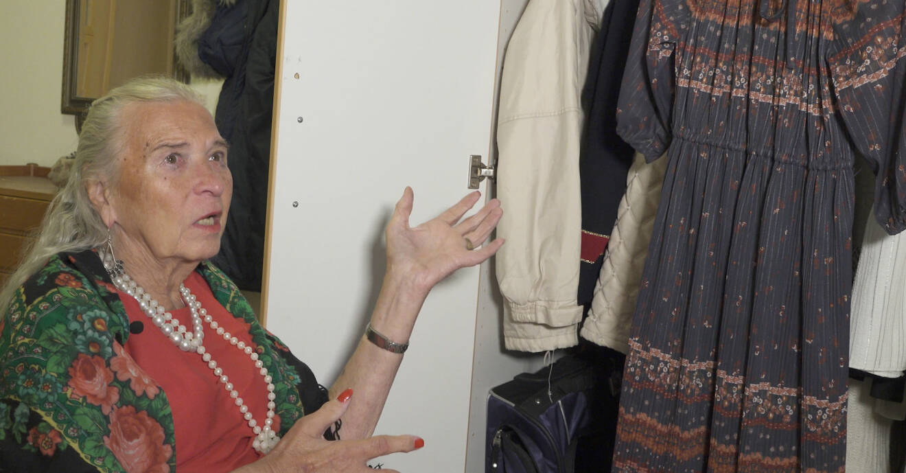 Birgitta Lundberg visar upp en garderob där det hänger kläder.