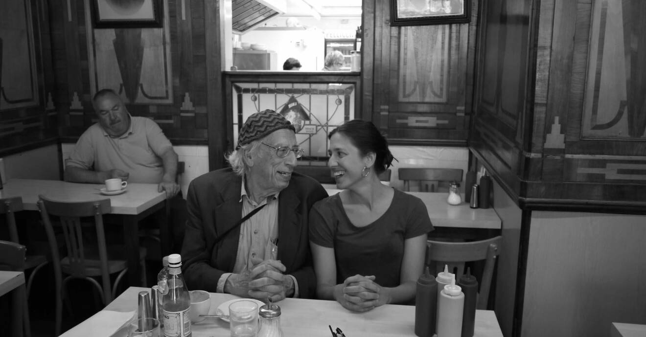 Izzy Young och hans dotter Philomène Grandin sitter på en restaurang och ler stort mot varandra