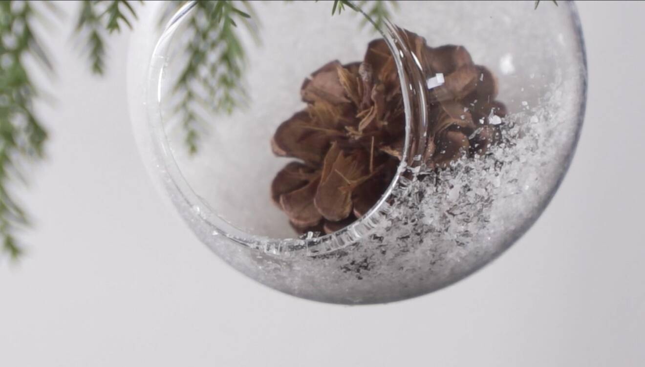 Julpyssel med julkula som dekoreras med självhäftande snö och juliga dekorationer som kottar, grankvistar eller figurer.
