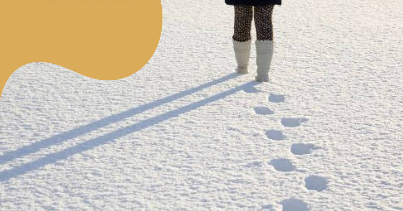 Kvinna promenerar i snön och lämnar spår efter sig.