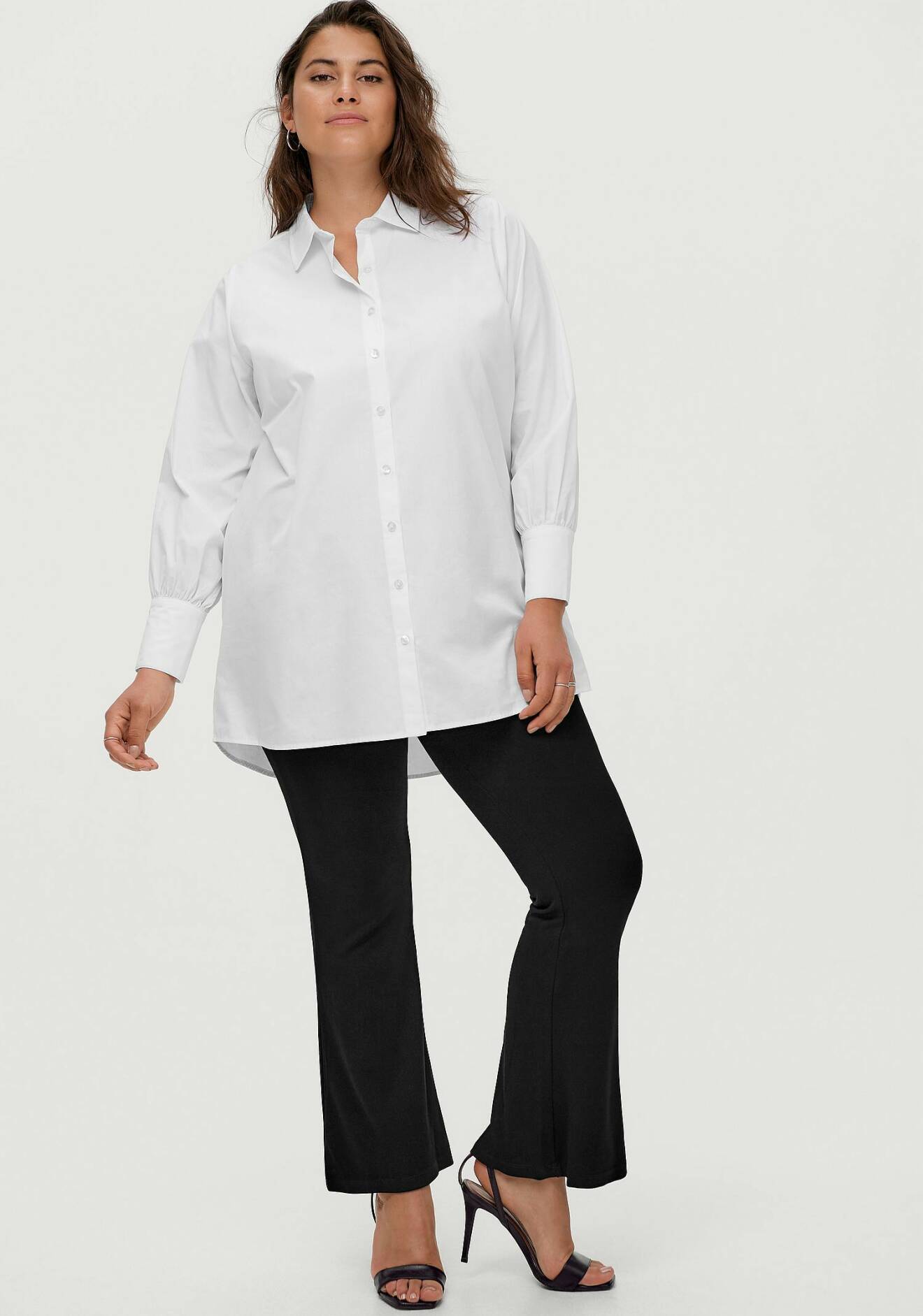 Kvinna med vit skjorta och svarta byxor.