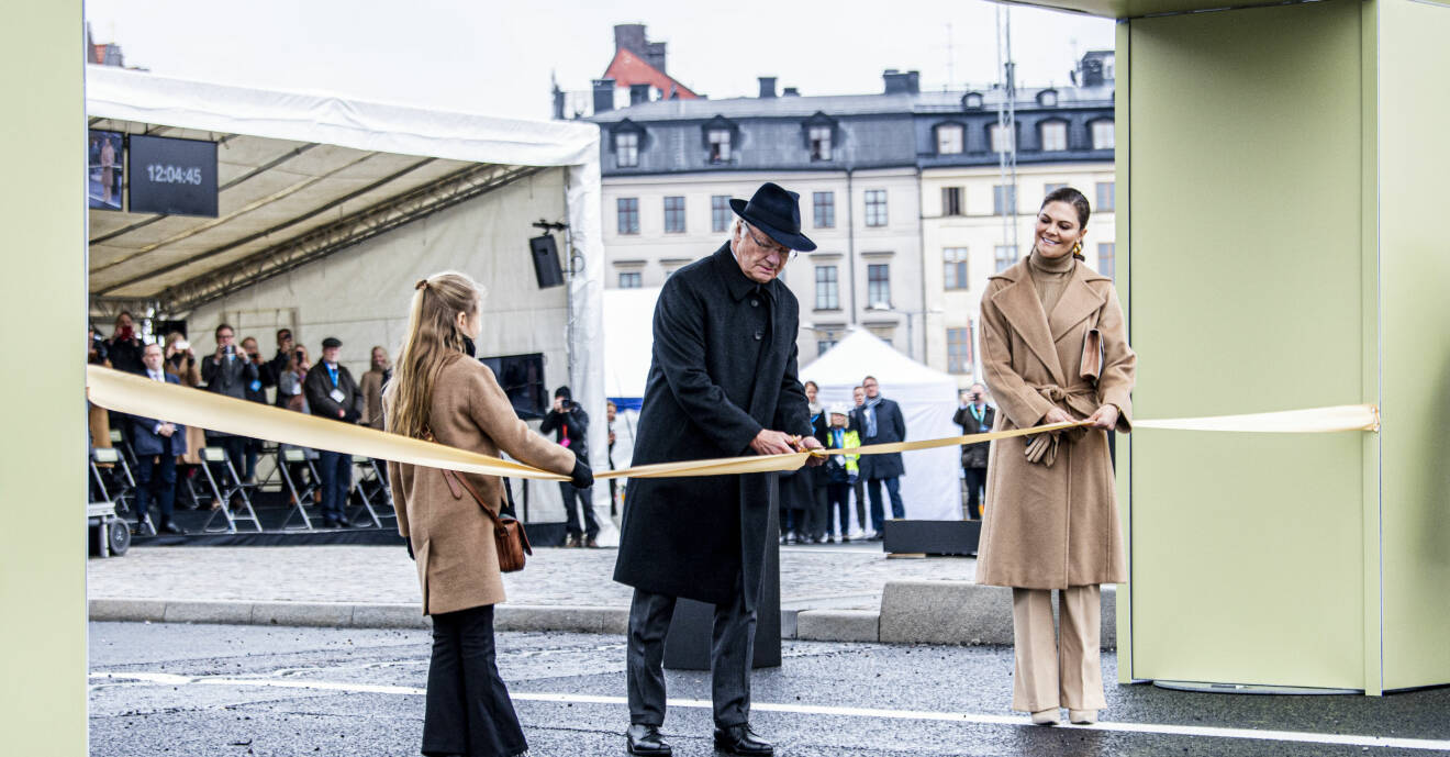 Kung Carl XVI Gustaf klipper bandet när Slussbron i Stockholm invigs. Vid hans sida finns kronprinsessan Victoria och prinsessan Estelle.