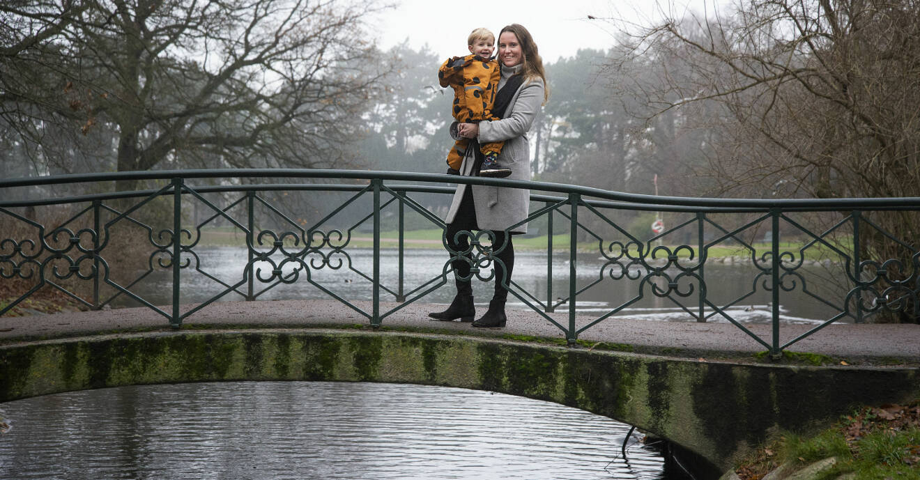 Ebba Andersson med sonen Theodore i famnen, fotograferade på en bro i Slottsparken i Malmö.