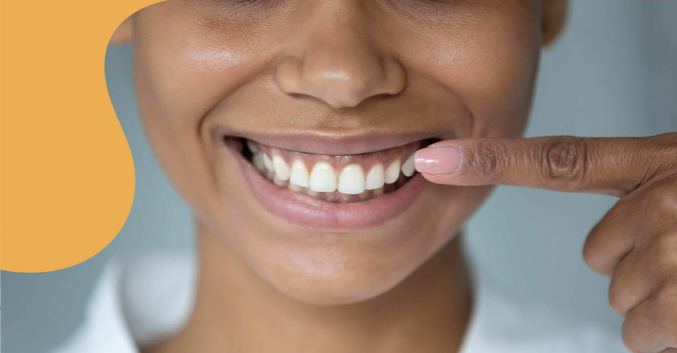 En leende kvinna pekar på sina tänder för att visa var plack vanligtvis sätter sig.