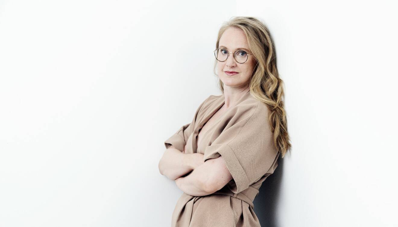 Författaren och tyngdlyftsningstränaren Sara Martinsson lutar sig mot väggen och berättar om varför hon skrev sin bok Knäböj – Om kvinnor och styrketräning.