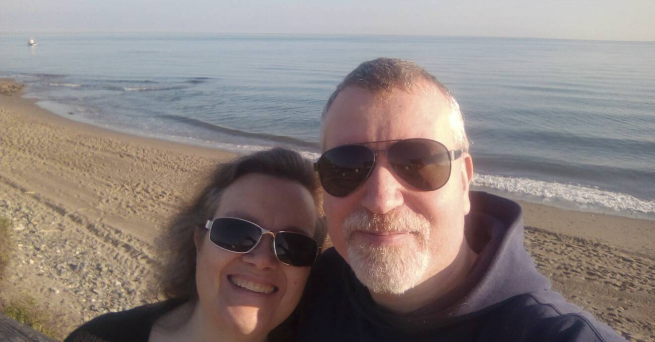 Carina och Thomas står på stranden vid vattenbrynet i Marbella där de bodde 2020.