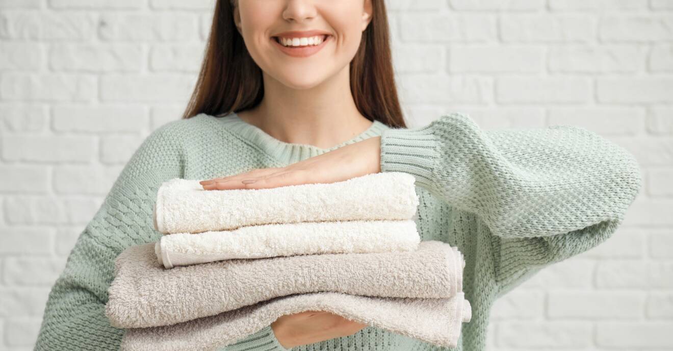 En kvinna som håller i en hög med handdukar som blivit rena tack vare ättika