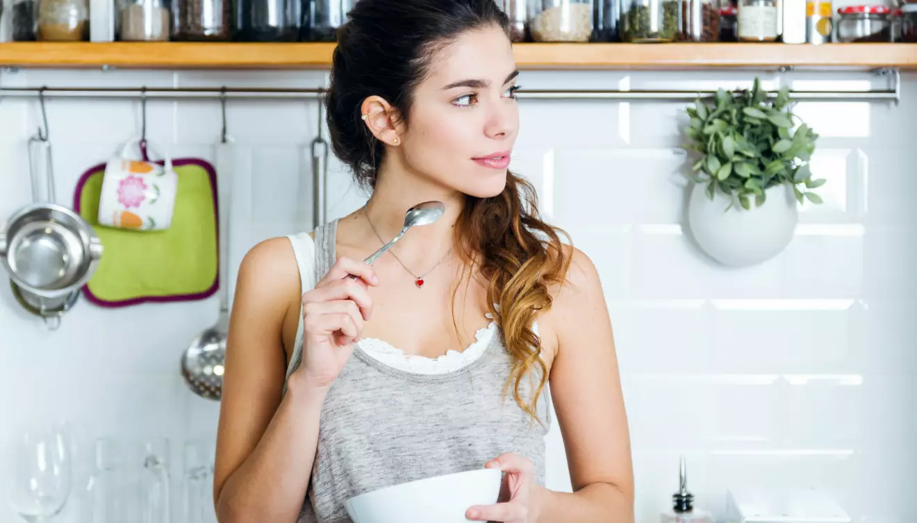 En kvinna äter youghurt för att få i sig proteiner efter träningspasset.