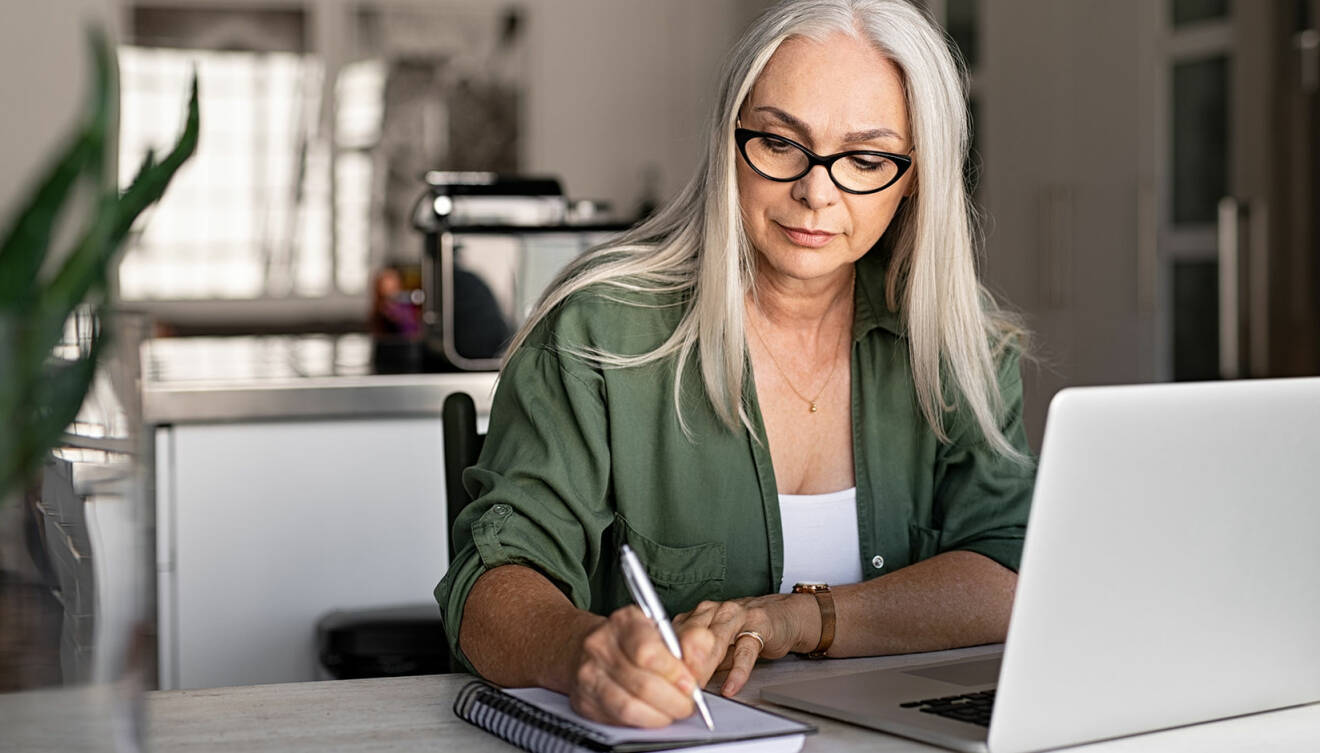 En kvinna sitter och skriver för hand istället för att anteckna på datorn.
