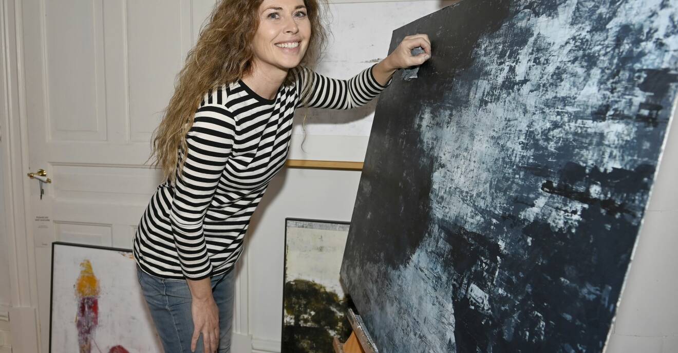 Maria Krall satsar på att måla. Här står hon framför staffliet där en abstrakt tavla i blåskala är placerad.