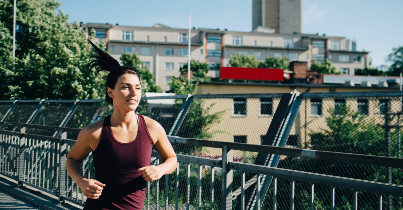 Kvinna joggar på bro i stad