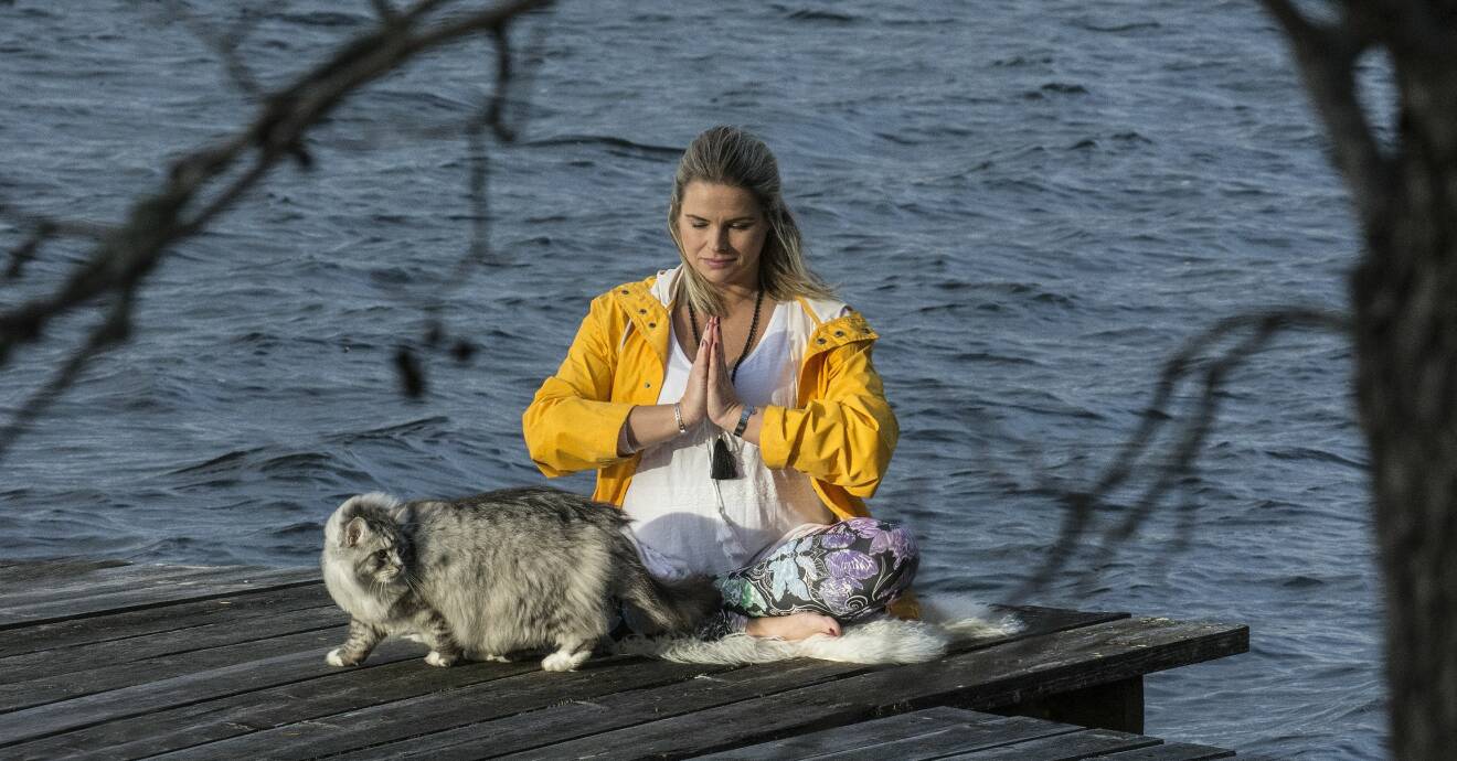 Kvinna sitter vid sjö och mediterar, för att lindra utmattning.