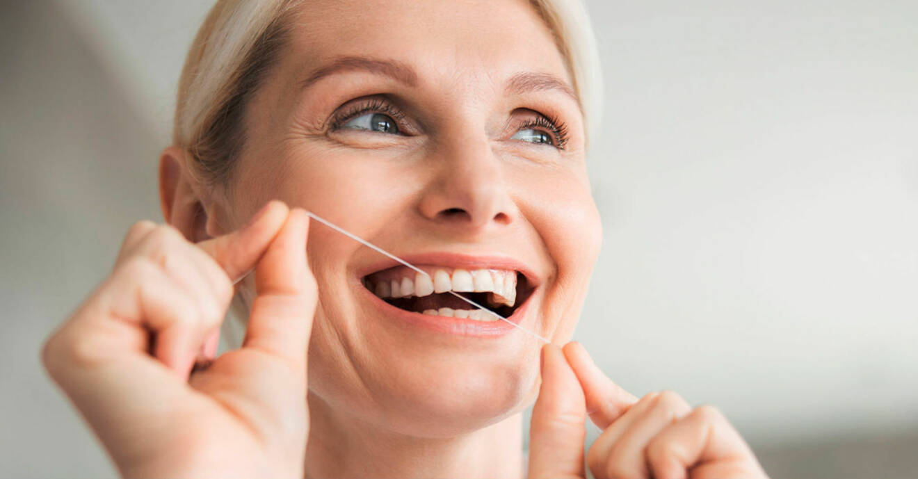 Kvinna gör rent mellan tänderna med tandtråd.