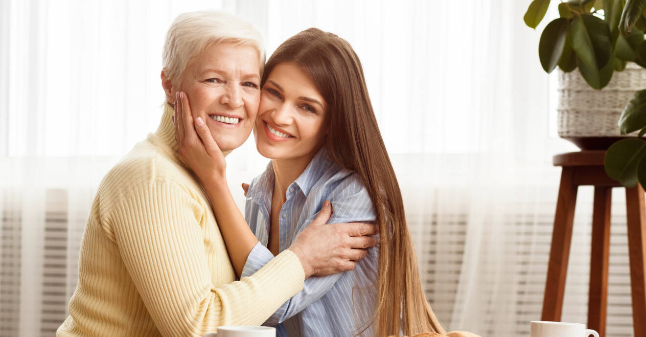 Äldre och yngre kvinna kramar leende om varandra.