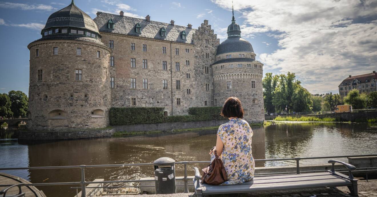 Åsa Avdic sitter på en bänk och tittar på Örebro slott.