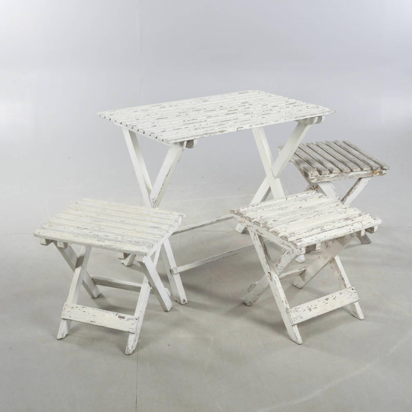 Bord och tre stolar utan ryggstöd i slitet vitt trä.
