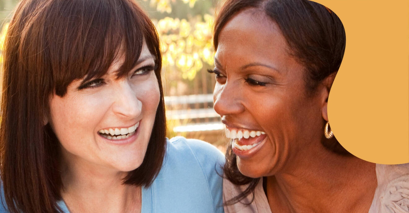 Två kvinnor skrattar utomhs.