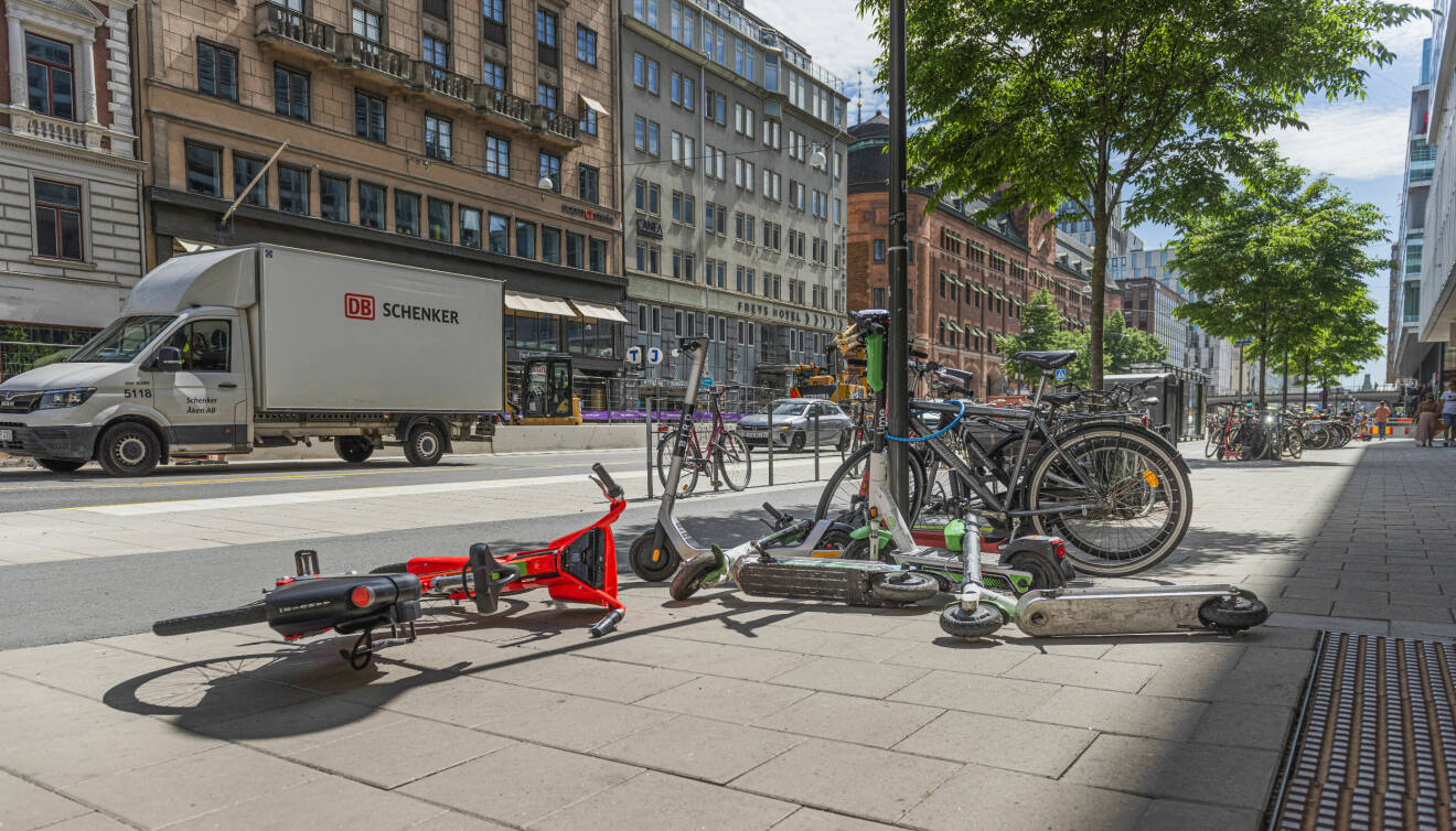 Elsparkcyklar och vanliga cyklar som ligger på gatan och trottoaren, slarvigt slängda.