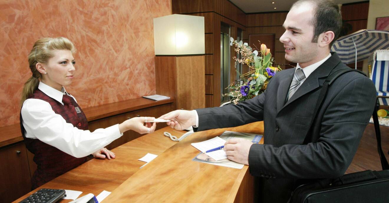 En kvinnlig receptionist ger en manlig hotellgäst sin rumsnyckel.