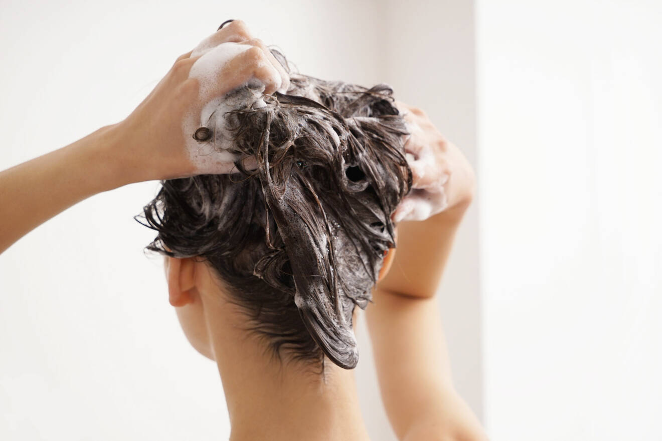Kvinna syns bakifrån när hon tvättar sitt hår.