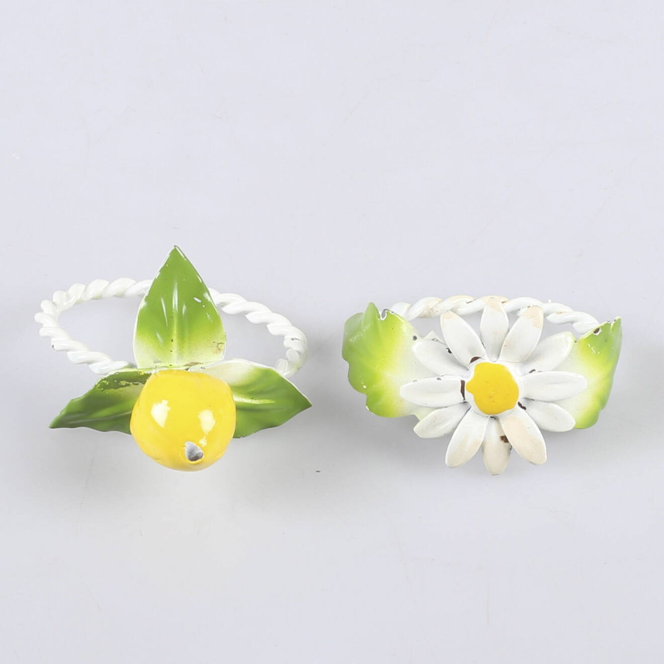 Två servettringar i metall med blomma och citron.