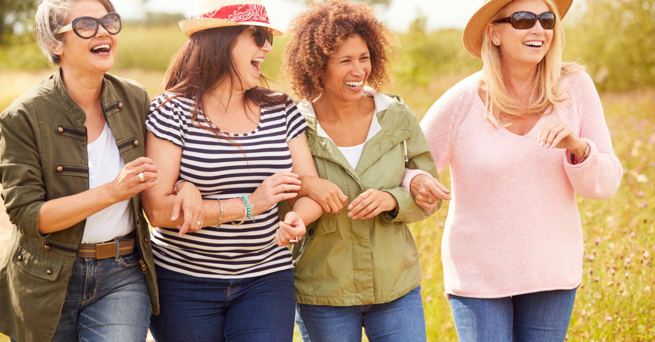 Fyra skrattande kvinnor på promenad.