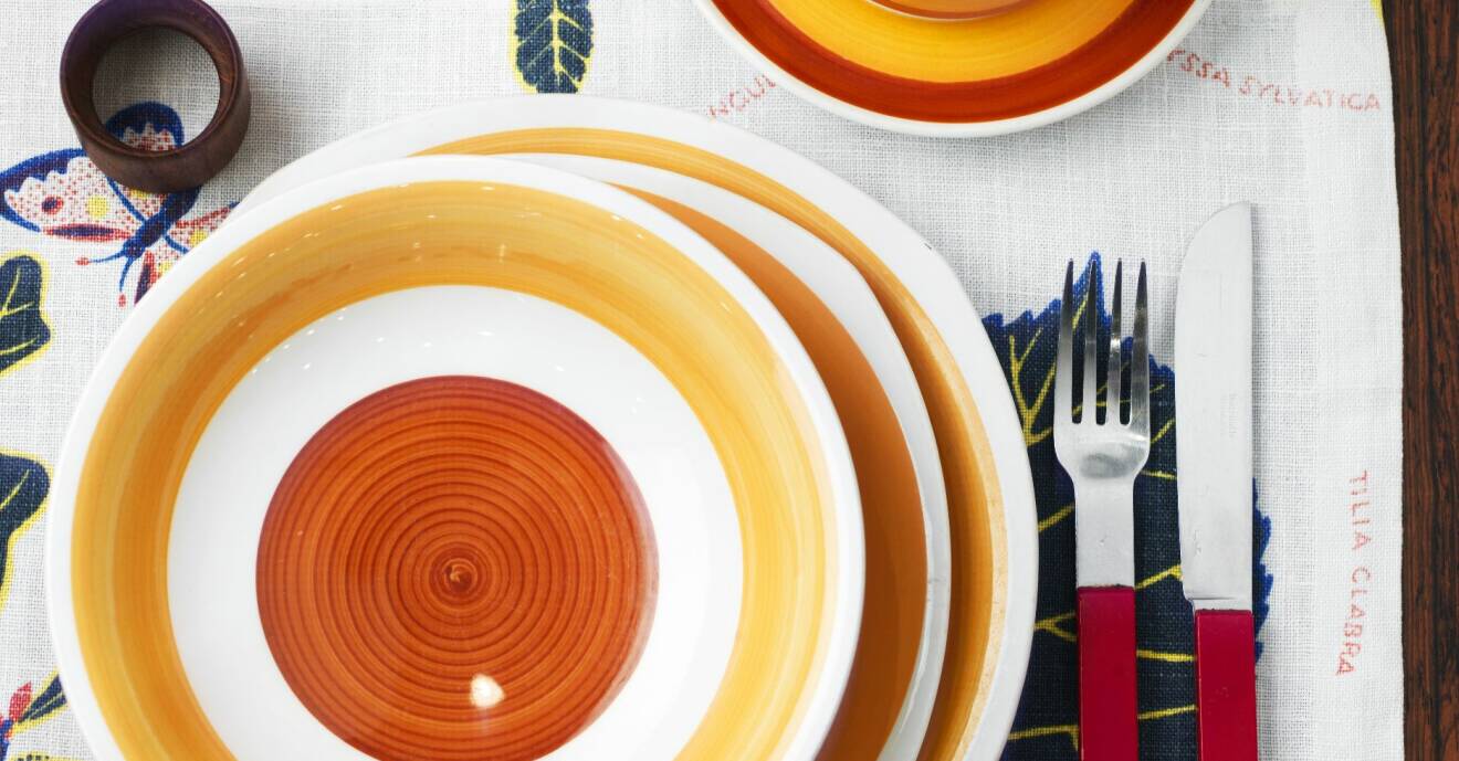 Dukat bord med färgglatt porslin i orange och gula toner.