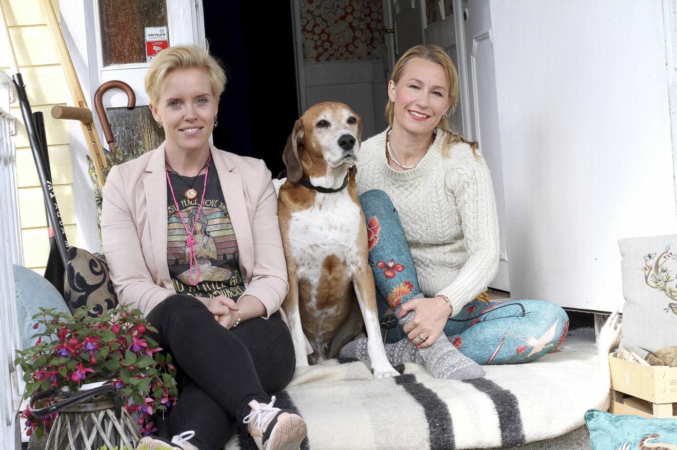 Malin Törnqvist och Lisa Karinsdotter sitter på trappan med en hund mellan sig.