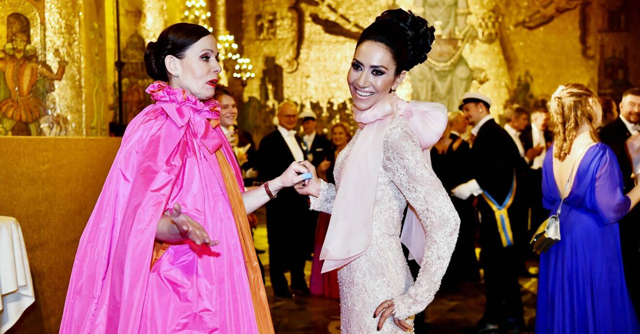 Sara Danius i knallrosa och orange klänning och Mouna Esmaeilzadeh under Nobelfesten 2018.