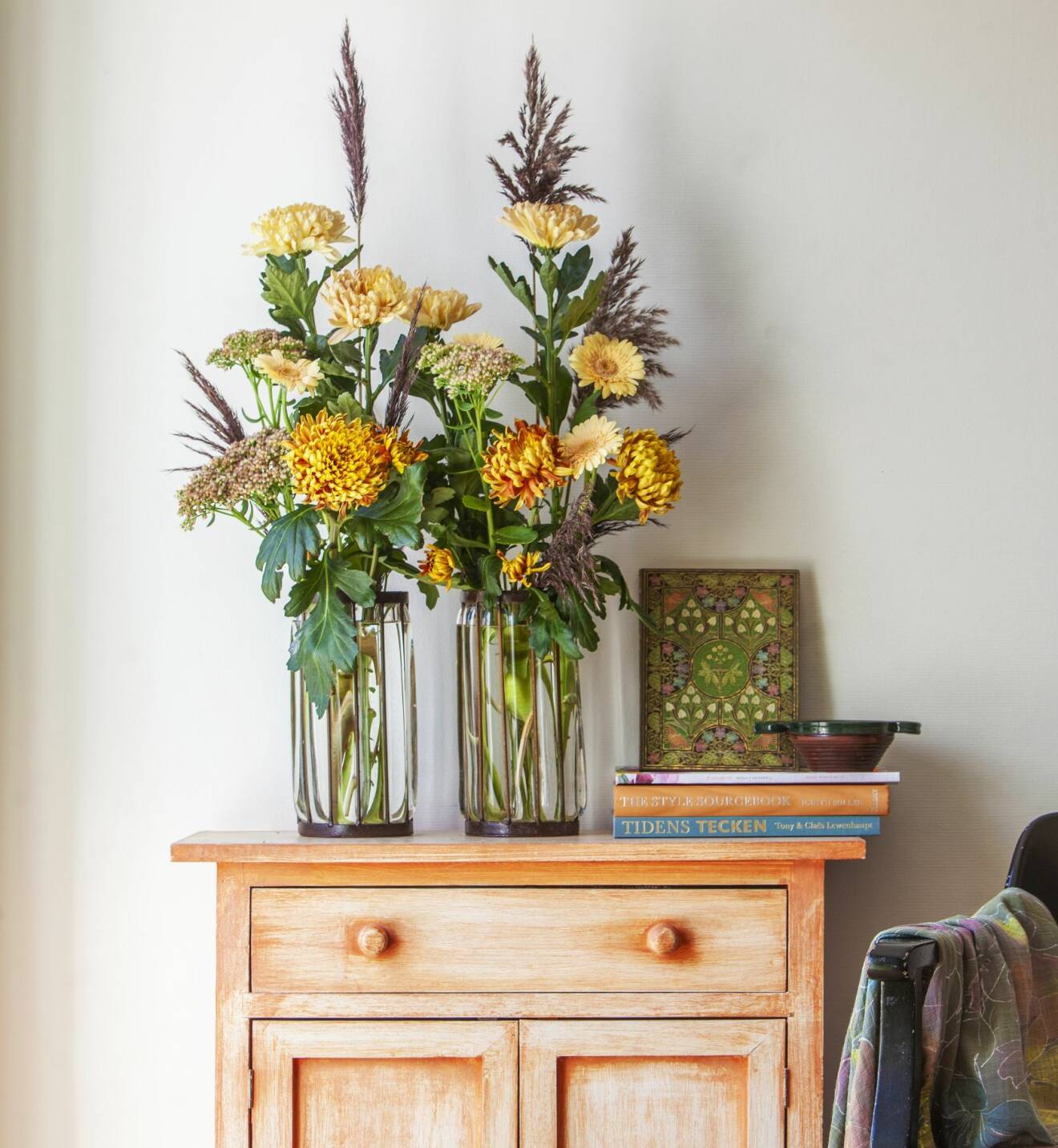 Sätt två likadana vaser bredvid varandra och fyll upp med ståtliga krysantemum ’Deco’ och ’Vass’. Här fick även någon germini (mini-gerbera) och kärleksört plats. Se till att byta vattnet varannan dag, så håller blommorna länge.