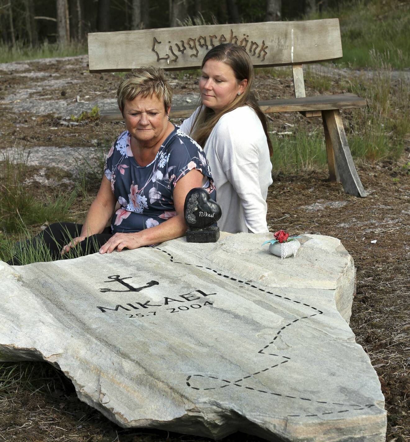 Lena och Linda sitter vid minnesplatsen som de byggt där minnesstenen är formad som kartbilden över Afrika och där en streckad linje påminner om Mikaels motorcykeläventyr.