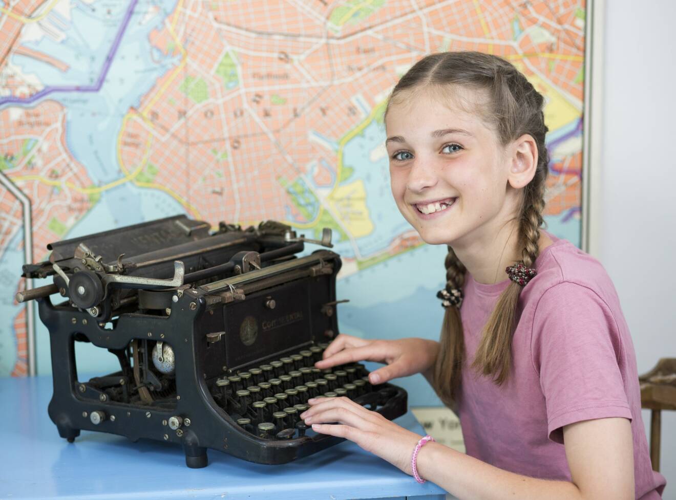 Ella sitter vid en antik skrivmaskin och ler.
