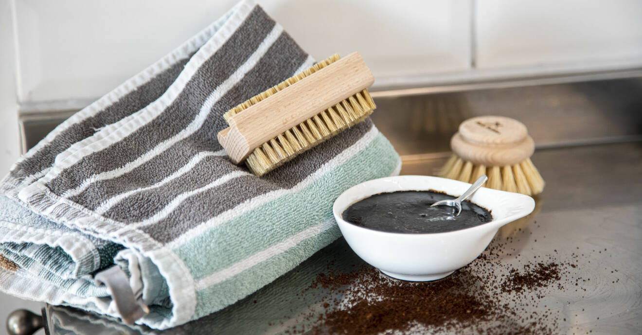 Kaffeskrubb med en handduk och nagelborste bakom. Kaffepulver ligger på diskbänken.