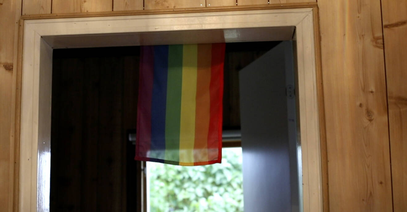 Prideflagga hänger ner framför dörrpost.